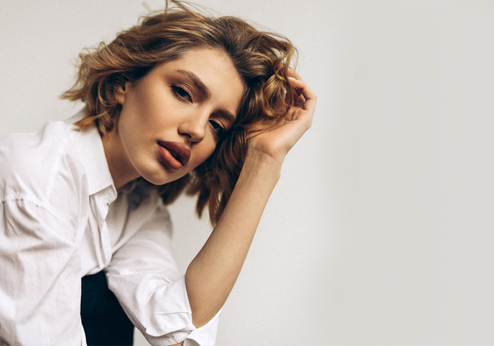 medspa patient model in a white button up shirt kneeling down